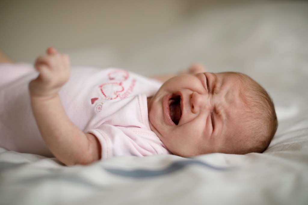 Newborn baby girl crying on a blanket